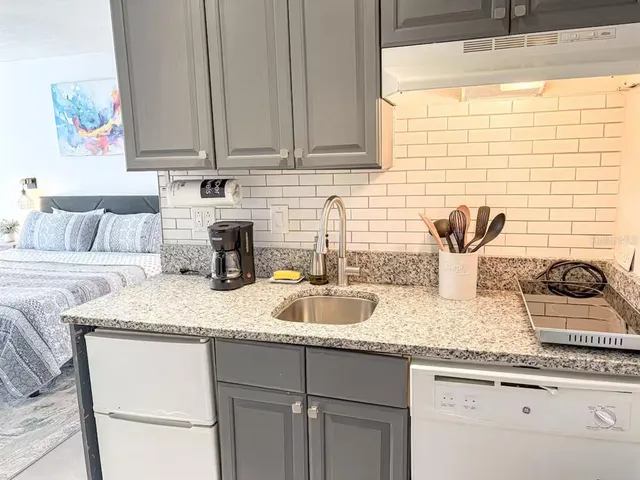 a kitchen with granite countertop a sink a stove and cabinets
