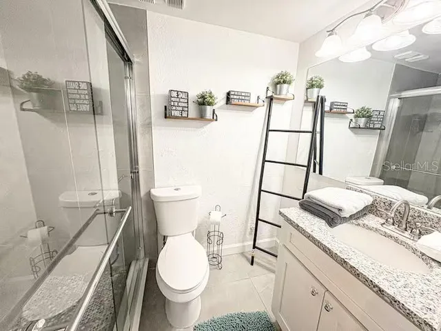 a bathroom with a granite countertop sink a toilet and a mirror