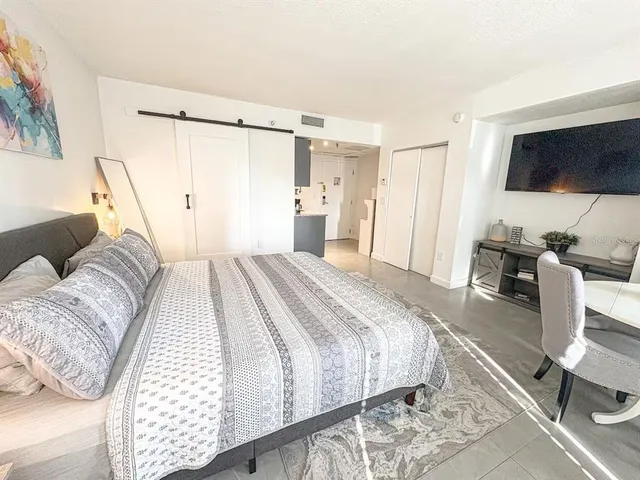 a spacious bedroom with a bed and a flat screen tv