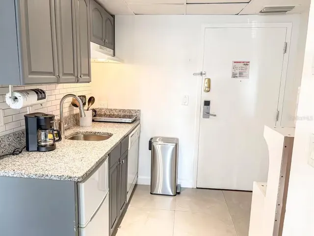 a kitchen with granite countertop a sink and a refrigerator