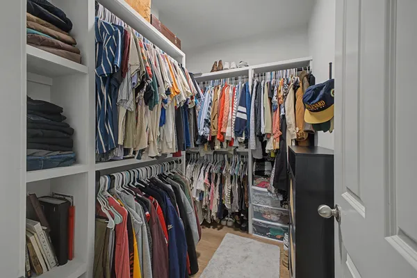a view of walk in closet with clothes and shoes
