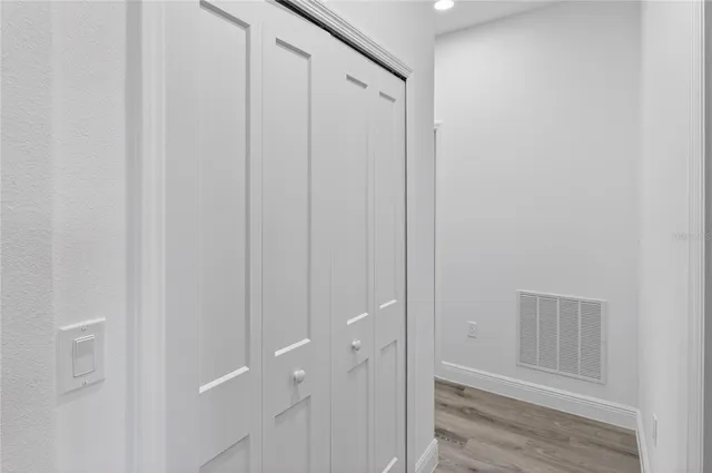 a view of a hallway with wooden floor and closet