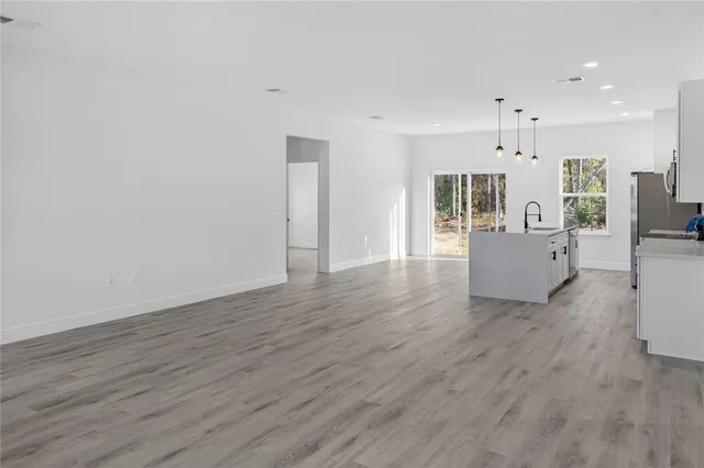 a living room with hard wood floors and kitchen view