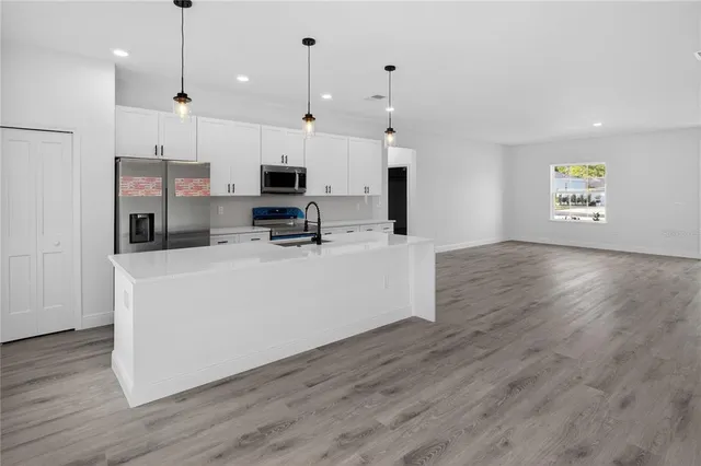 a view of a kitchen with kitchen island stainless steel appliances a stove a sink a refrigerator and cabinets