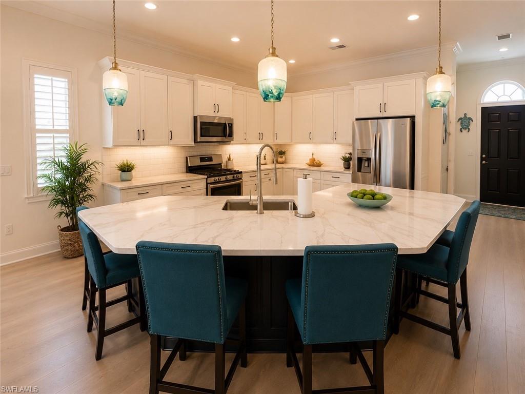 6574 Amarone Lane Naples, FL 34113 - Photo 10 of 44 a kitchen with stainless steel appliances kitchen island granite countertop a dining table chairs and a refrigerator
