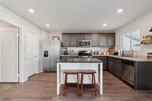 a kitchen with stainless steel appliances granite countertop a stove top oven a sink and dishwasher with wooden floor