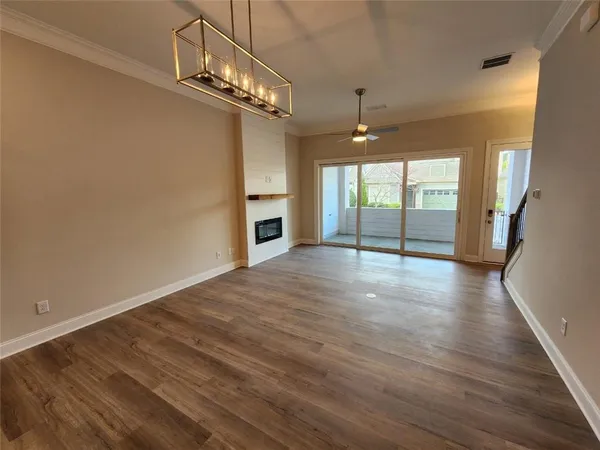 a view of a kitchen with a sink a kitchen island a refrigerator a ceiling fan and wooden floor