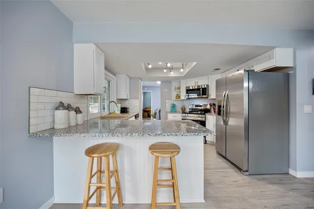 a kitchen with stainless steel appliances granite countertop a refrigerator and a stove top oven