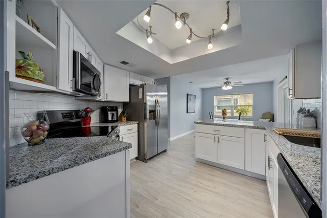 a large kitchen with stainless steel appliances granite countertop a lot of counter space and wooden floor