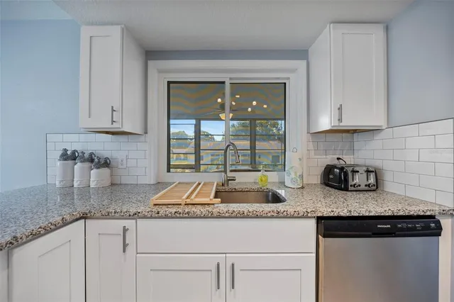 a kitchen with granite countertop a sink stove and cabinets