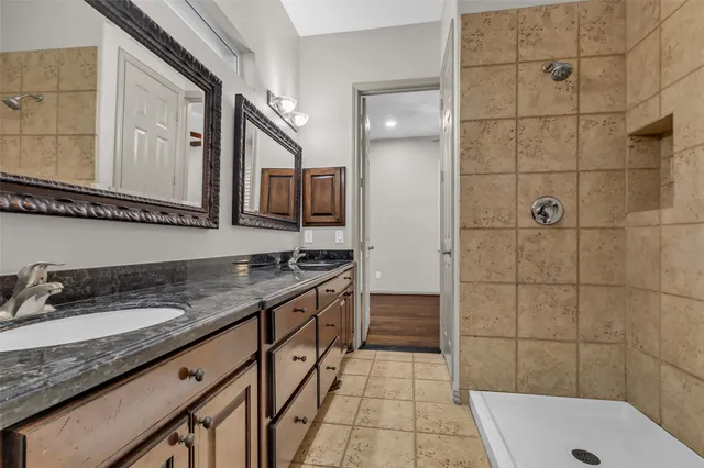 a bathroom with a granite countertop sink a mirror and shower