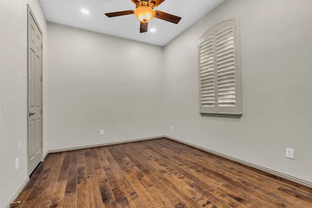 an empty room with a ceiling fan and wooden floor