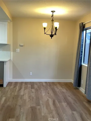 a view of a room with a hanging light and hardwood