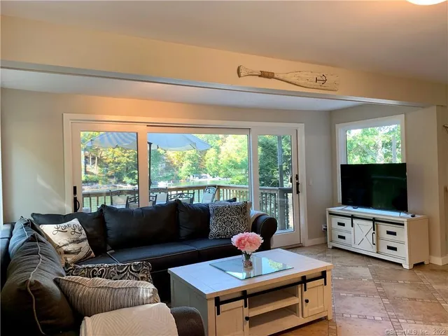 a living room with furniture a flat screen tv and a floor to ceiling window
