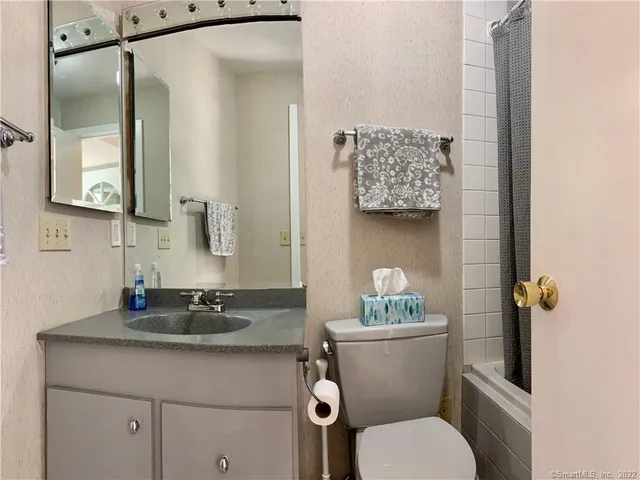 a bathroom with a granite countertop sink a mirror and a toilet