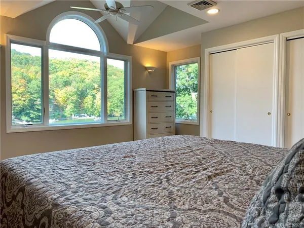 a bed sitting in a spacious bedroom next to a window