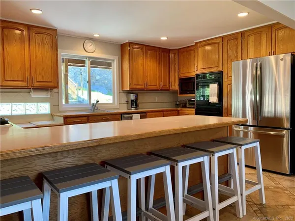 a kitchen with stainless steel appliances a refrigerator a sink a stove and white cabinets with wooden floor