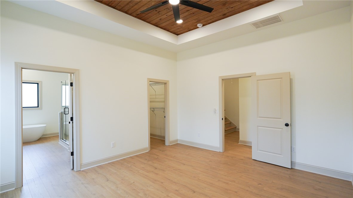 1001 Five Forks Road Pendleton, SC 29670 - Photo 28 of 43 This spacious primary bedroom features a striking wood-paneled tray ceiling and durable laminate flooring.