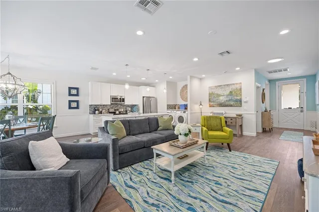 a kitchen with stainless steel appliances a stove a refrigerator a sink with white cabinets and wooden floor