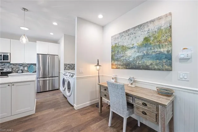 a kitchen with a refrigerator a stove a sink dishwasher a dining table and chairs with wooden floor