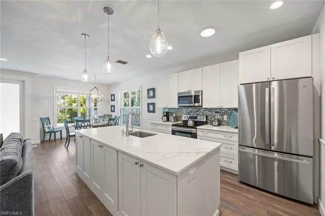a kitchen with a sink a stove a refrigerator and white cabinets with wooden floor