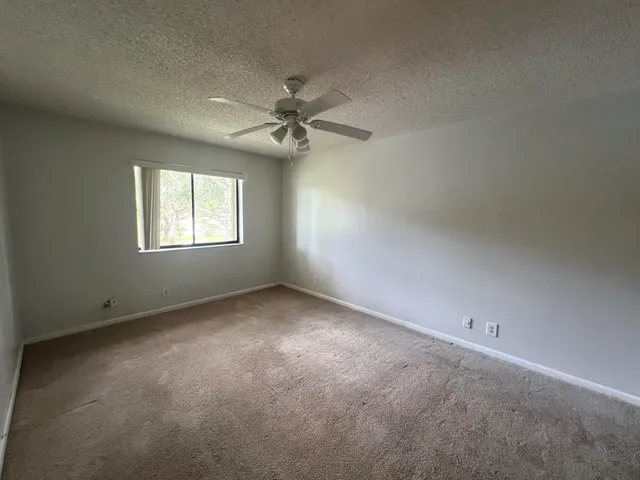 an empty room with windows and ceiling fan view