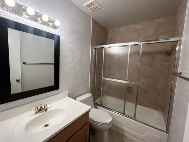 a bathroom with a shower a sink a toilet and mirror