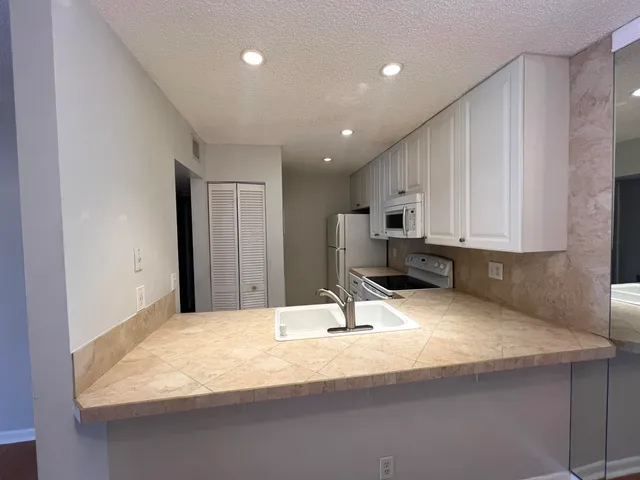 a kitchen with stainless steel appliances kitchen island sink refrigerator and cabinets