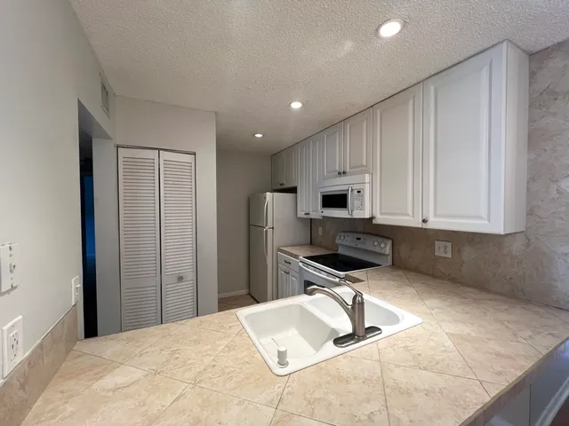 a kitchen with granite countertop a refrigerator sink and cabinets