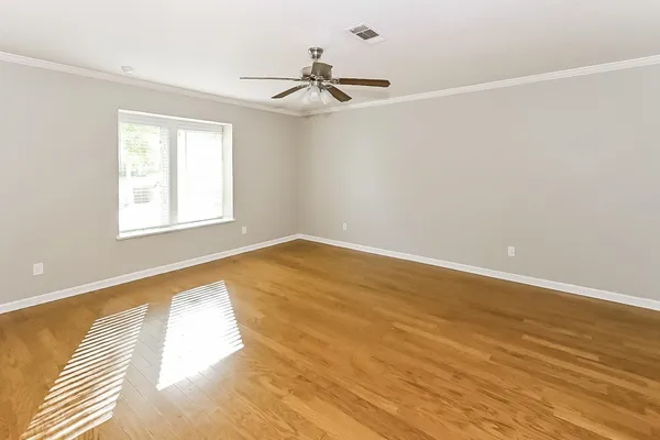 an empty room with wooden floor fan and windows