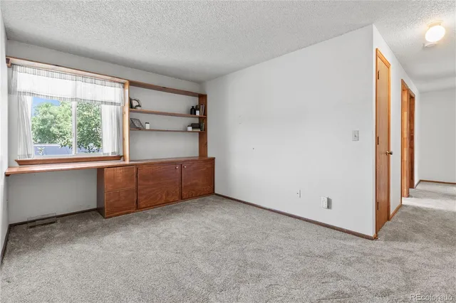 an empty room with a window and a refrigerator