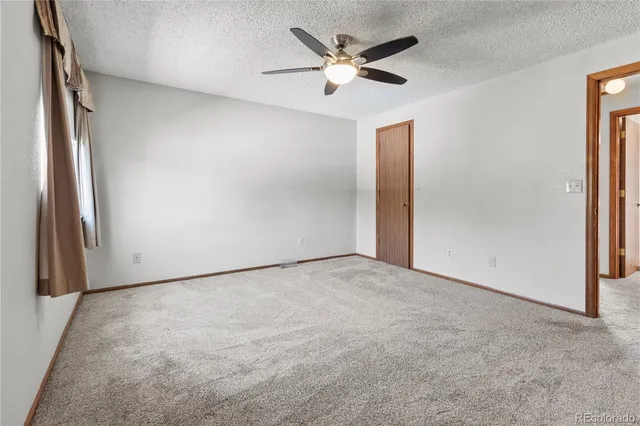 an empty room with a windows and a ceiling fan