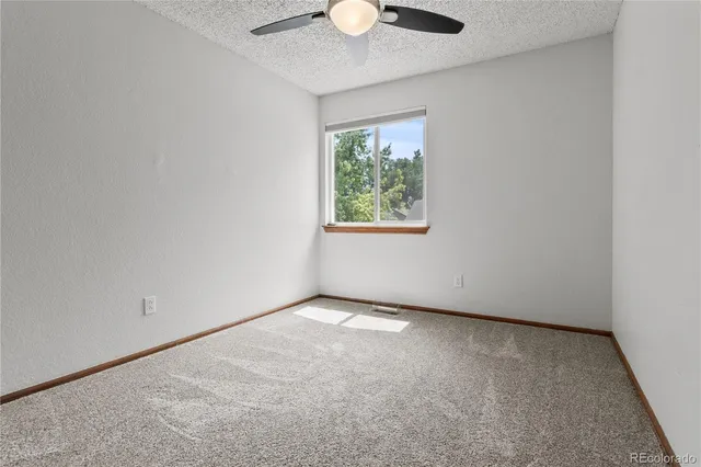an empty room with chandelier fan and windows