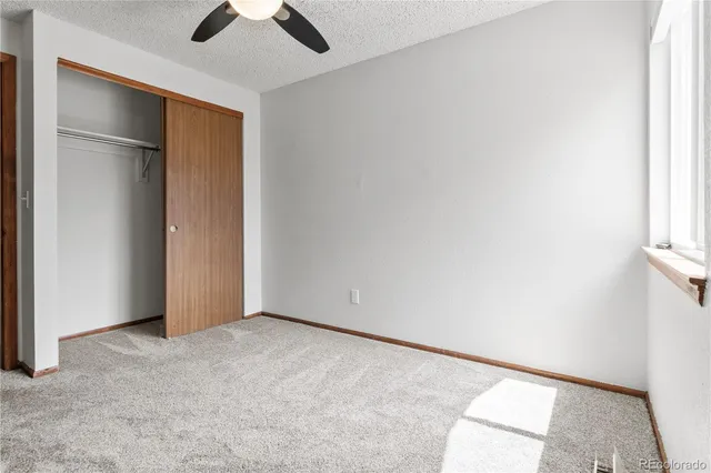 an empty room with ceiling fan and window