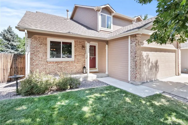 a view of a house with brick walls and a yard with plants