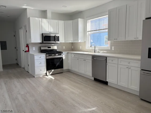 a kitchen with stainless steel appliances granite countertop a stove top oven a sink dishwasher and white cabinets