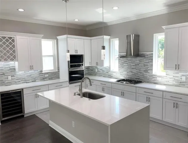 a kitchen with stainless steel appliances a sink a stove a microwave a center island and cabinets