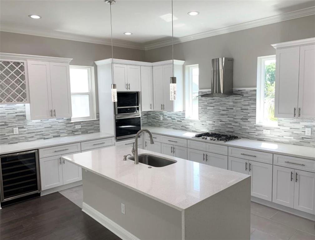 3702 West Roland Street, Unit 13 Tampa, FL 33609 - Photo 7 of 10 a kitchen with stainless steel appliances a sink a stove a microwave a center island and cabinets