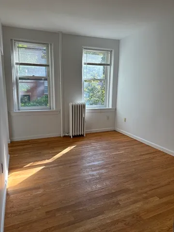 a view of empty room with window and wooden floor