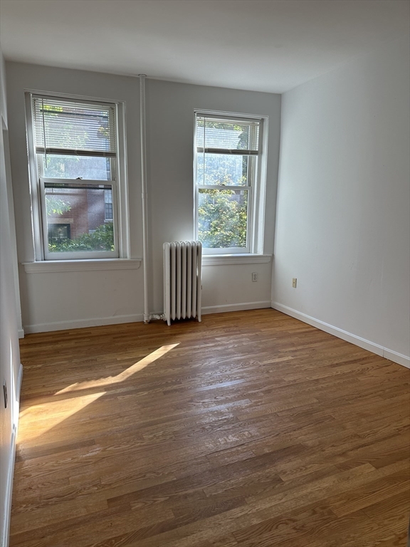 a view of empty room with window and wooden floor
