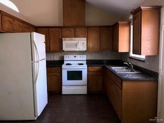 2213 West Candlelight Lane, Unit 4 Edinburg, TX 78541 - Photo 3 of 15 Kitchen featuring white appliances, dark countertops, vaulted ceiling, and brown cabinetry