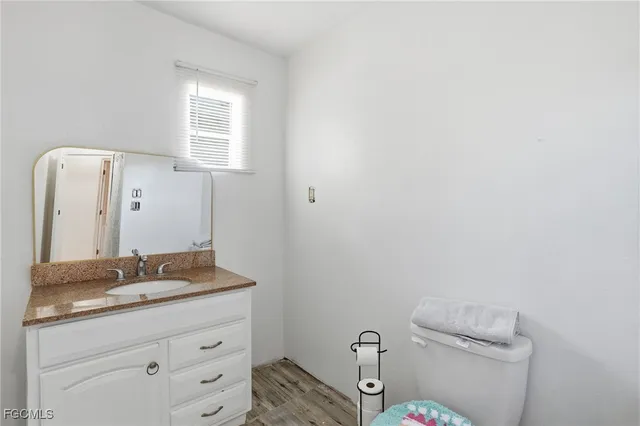 a bathroom with a granite countertop toilet sink and mirror