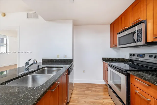 a kitchen with granite countertop a sink and stove top oven
