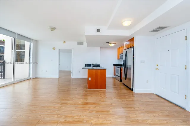 a view of kitchen with stainless steel appliances granite countertop a refrigerator and a wooden floor