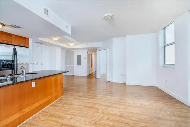 a view of a kitchen with kitchen island a sink wooden floor and a large window