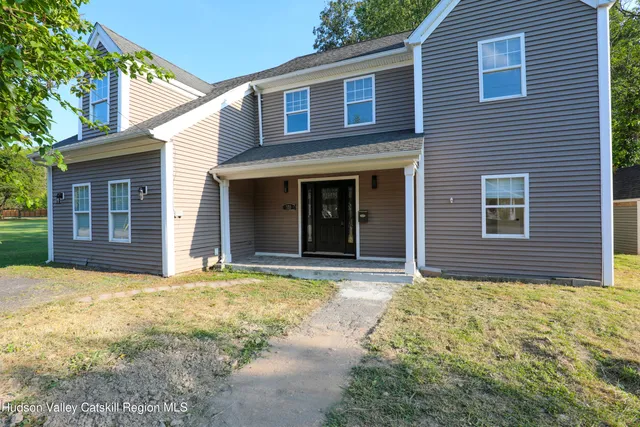 a view of a brick house with large windows and a yard