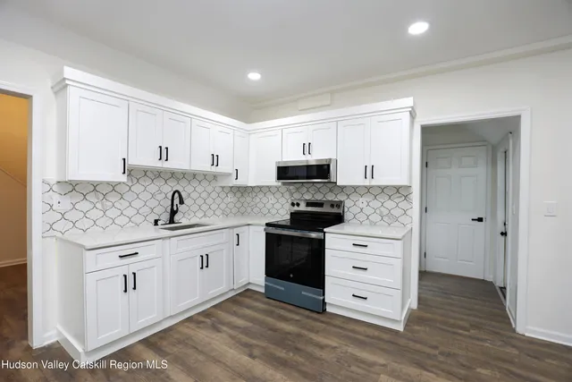 a kitchen with stainless steel appliances granite countertop a sink and cabinets with wooden floors