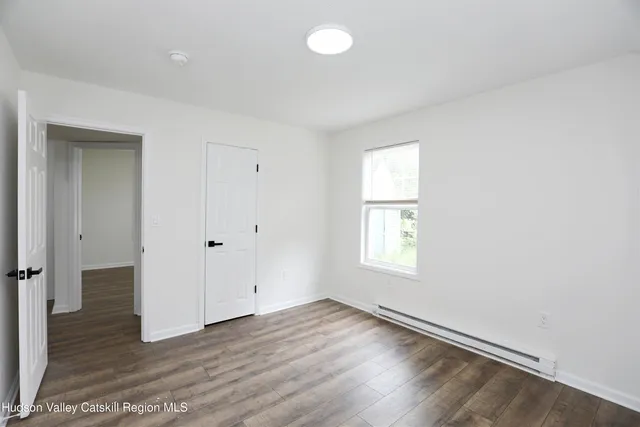 an empty room with wooden floor and window