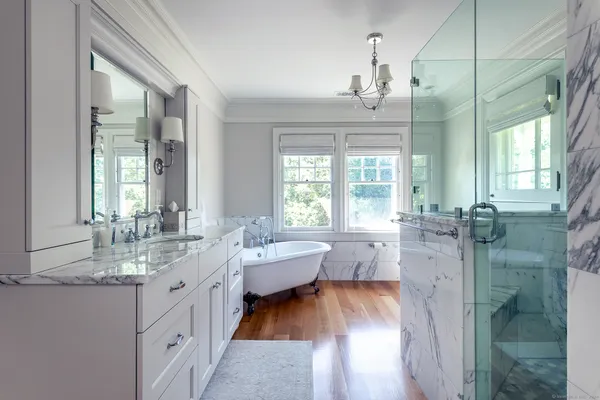 a bathroom with double vanity sinks a large mirror and a bath tub