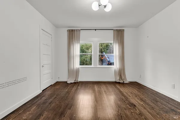 a view of an empty room with wooden floor fire place and a fireplace